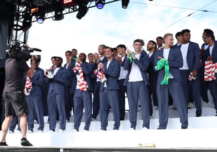 The players applaud on stage while wearing blue suits over white T-shirts