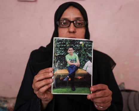 Mother of Palestinian child Mohammad Abdul Zinati, who died while trying to help injured medical worker, holding a photo of him while sitting on a sofa.