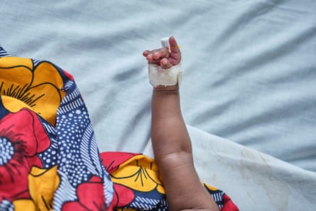 A babe wrapped successful a agleam African people pinch a bandage and cannula connected its manus