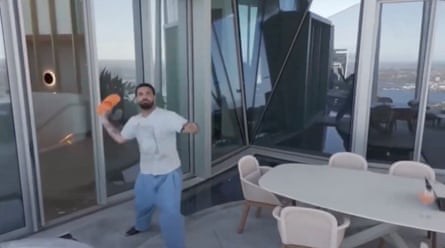 A man in white T-shirt and jeans poised to throw a bright orange slider at something in the air on his patio