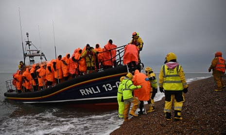 People picked up at sea trying to cross the Channel are helped ashore from an RNLI lifeboat at Dungeness, Kent, in December