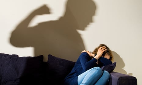 Shadow of a man with a clenched fist over a cowering woman cowers