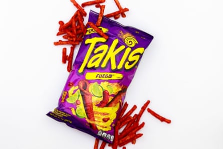 A packet of Takis Fuego, with some of the snacks outside the pack