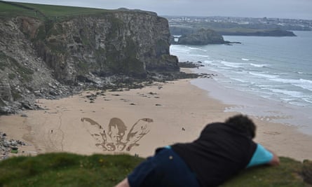 A sand drawing calls on world leaders to ‘share the vaccine and waive the patent’ at Watergate Bay near Newquay, Cornwall.