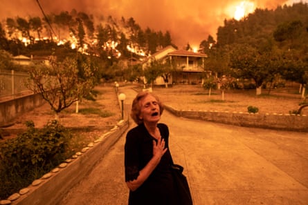An elderly resident reacts as a wildfire approaches her house in the village of Gouves, on the island of Evia, Greece, on Sunday August 8 2021