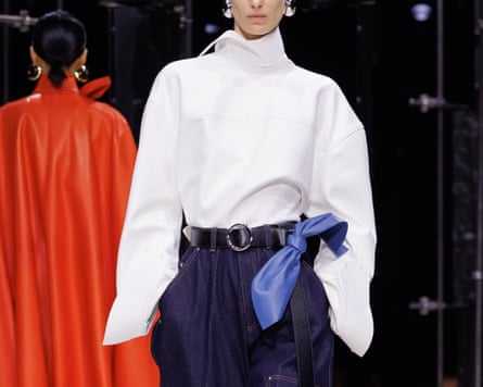 A runway model wears a white turtleneck, belted navy wide-leg trousers and blue scarf at Givenchy