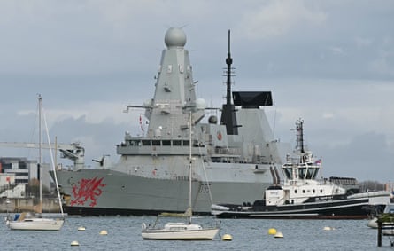 HMS Dragon, a Royal Navy Type 45 Daring-class air-defence destroyer warship, is guided by tug boats as it departs Portsmouth