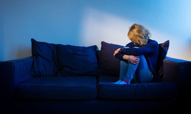 Awoman sat on sofa showing signs of depression