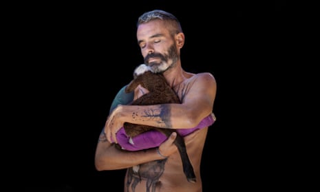 Armoní the lamb being held in the arms of Gaia animal sanctuary founder Coque Fernández Abella, in Spain