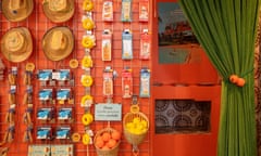 Accessories hang on an orange wall next to a changing room with a green fabric curtain pulled back