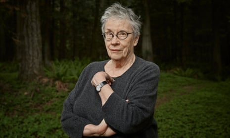 Annie Proulx in a jumper, with short hair and wearing glasses, arms crossed and with a quizzical expression
