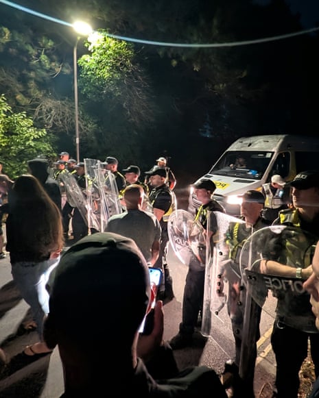 Police officers hold up riot shields at the scene of unrest near Eastney