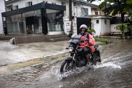 A motorcyclist rides along a flooded street in Lagos, Nigeria