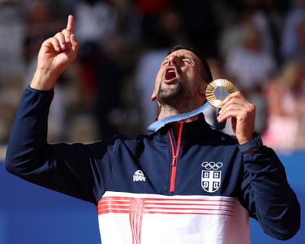 Novak Djokovic gestures to the sky while holding his gold medal at the Paris Olympics