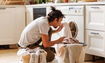 Young african american male householder loading washing machine