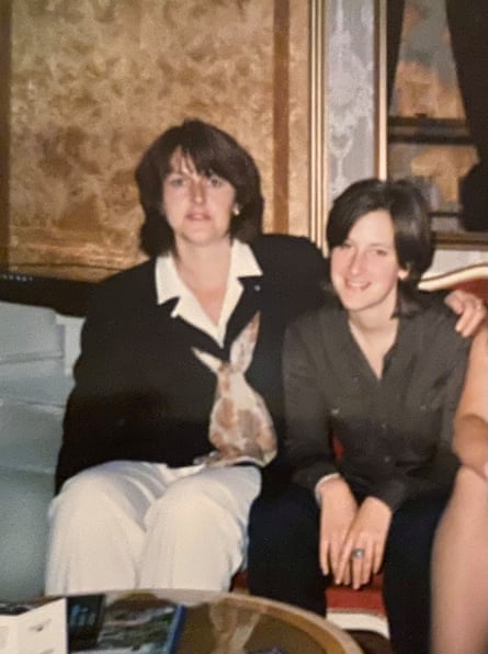 A smartly dressed middle aged woman with her arm around and younger woman who is smiling.