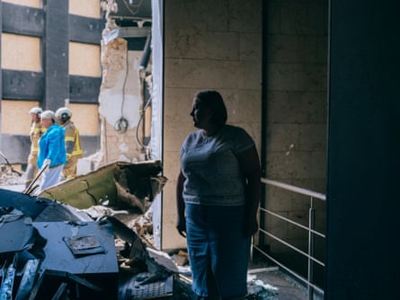 A woman stands among debris and damaged walls in Ukraine