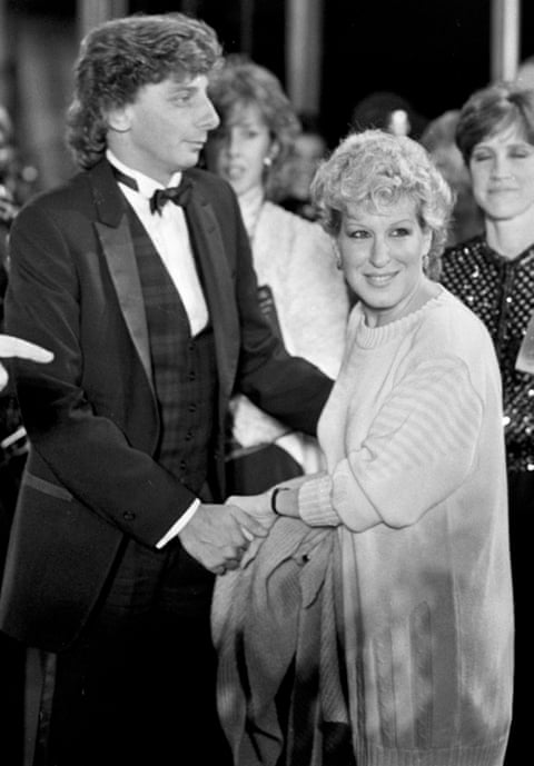 Black and white image of Barry Manilow wearing a tuxedo holding Bette Midler’s hand