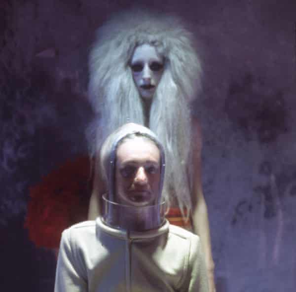 She has a long, woolly white wig, black eyes in a white face;  he defies description