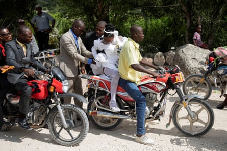 A pregnant bride and her groom travel by motorbike to their reception after getting married in a double wedding ceremony in Baie-de-Henne, Nord Ouest department