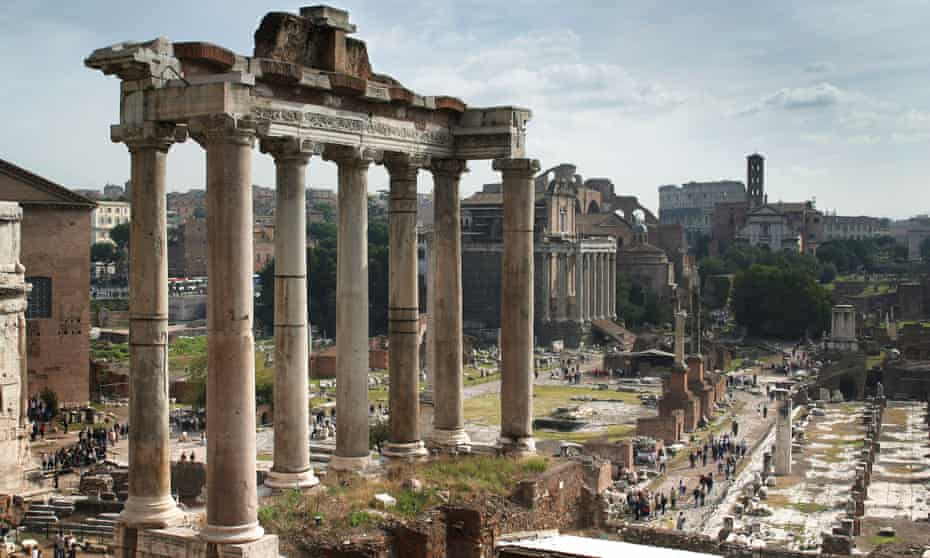 The Temple of Saturn with the Colosseum in the far distance. The Forum, Rome, Italy.