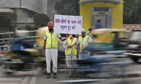 Volunteers in Delhi stand at a busy crossing with a banner saying: ‘Obey odd and even, remove pollution’.