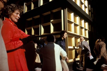 People walking past a gold-coloured wall with square shapes
