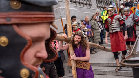 Jesus actor carrying the cross down some steps