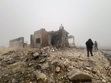 Syrians stand in the midst of rubble, staring at an abandoned medical facility with no roof that was hit by Iranian missiles.