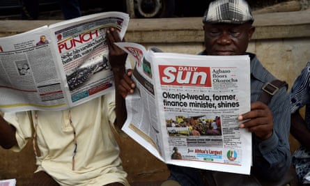 A man reads a newspaper with a front-page story about the appointment of Ngozi Okonjo-Iweala as WTO president