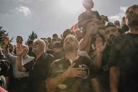 A crowd of people, some looking upwards, some with eyes closed, making gestures of worship