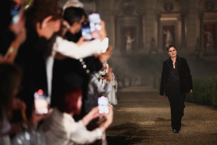 Maria Grazia Chiuri walking as people take photos on phones