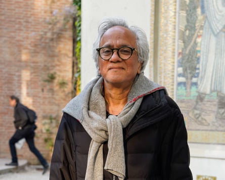 Artist Anish Kapoor, wearing glasses, a dark top and a grey pullover wrapped over his shoulders