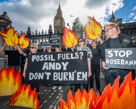 Protesters in front of the Houses of Parliament surrounded by cardboard cutout flames and signs reading ‘Fossil fuels? Andy don’t burn’em’ and ‘Stop Rosebank’