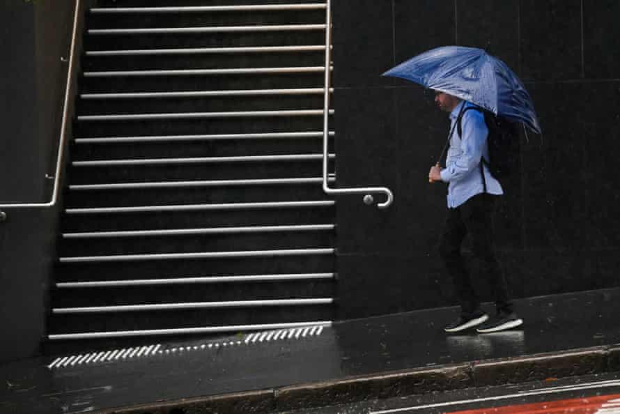 Des membres du public s'abritent de la pluie sous des parapluies à Sydney.