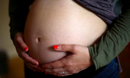 A pregnant woman holds her stomach.