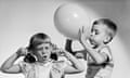Black-and-white image of two white children, perhaps from the 50s or made to look like it's from the 50s, with the little boy blowing up a balloon over the head of the little girl, who is grimacing with her eyes closed and sticking her fingers in her ears.