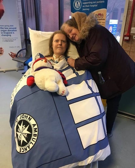 Woman with her arm around man covered by St John Ambulance blanket with cuddly toy