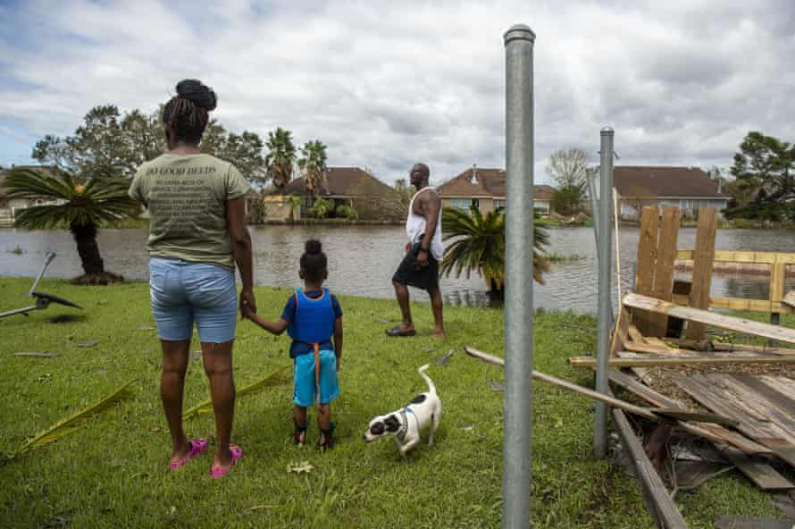 Wearing a life jacket for the walk through their flooded neighborhood, Royal Williams, four, holds the hand of his mother, Tarnequa, as they and Torris Williams, her father, along with their dog Marshall, survey the damage to their backyard in LaPlace, near New Orleans.