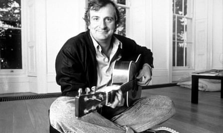 Douglas Adams, yere çapraz bacaklı oturuyor, gitar çalıyor