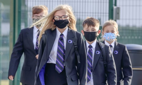 group of pupils in uniform walking towards camera in masks