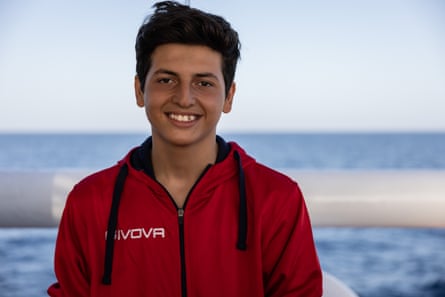 A boy wearing a red zip up top looks at the camera.