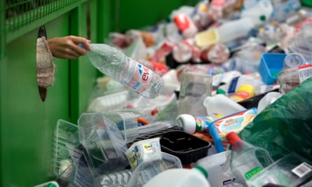 A woman depositing a plastic bottle in a recycling bin.