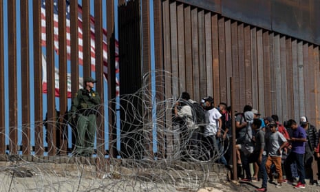 Central American migrants look through a border fence as US border patrol agents stand guard in Tijuana, Mexico, on 25 November 2018. 