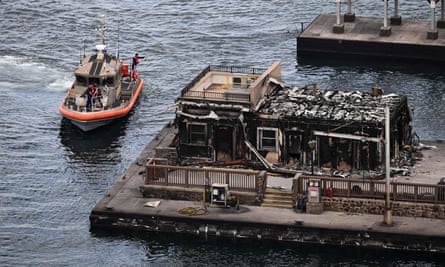 Bir ABD Sahil Güvenlik gemisi, tarihi Lahaina kasabasındaki yıkılmış bir binanın yakınındaki limana yanaşıyor.