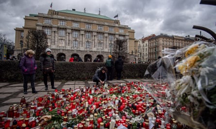 يقف الناس أمام مئات الشموع الموضوعة في الوقفة الاحتجاجية.
