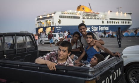 Refugees who took a boat from Turkey to Lesbos Island are seen behind a vehicle as they wait at a port to get a ferryboat to go to Athens.
