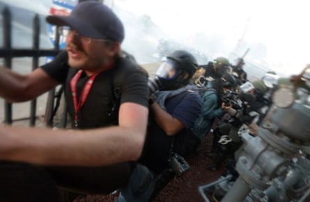 Journalist flee Minnesota State Patrol officers as they spray journalists with pepper spray and fire rubber bullets at them 30 May 2020 outside the 5th Precinct police station in Minneapolis