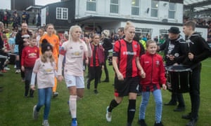 Lewes and Manchester United players walk on to the pitch at The Dripping Pan Stadium.