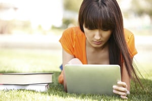 A girl reading from a digital tablet on the grass
